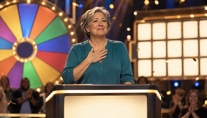 Illustration: a smiling contestant at a game show podium, hand on her heart, with a colourful prize wheel and blank puzzle tiles behind her